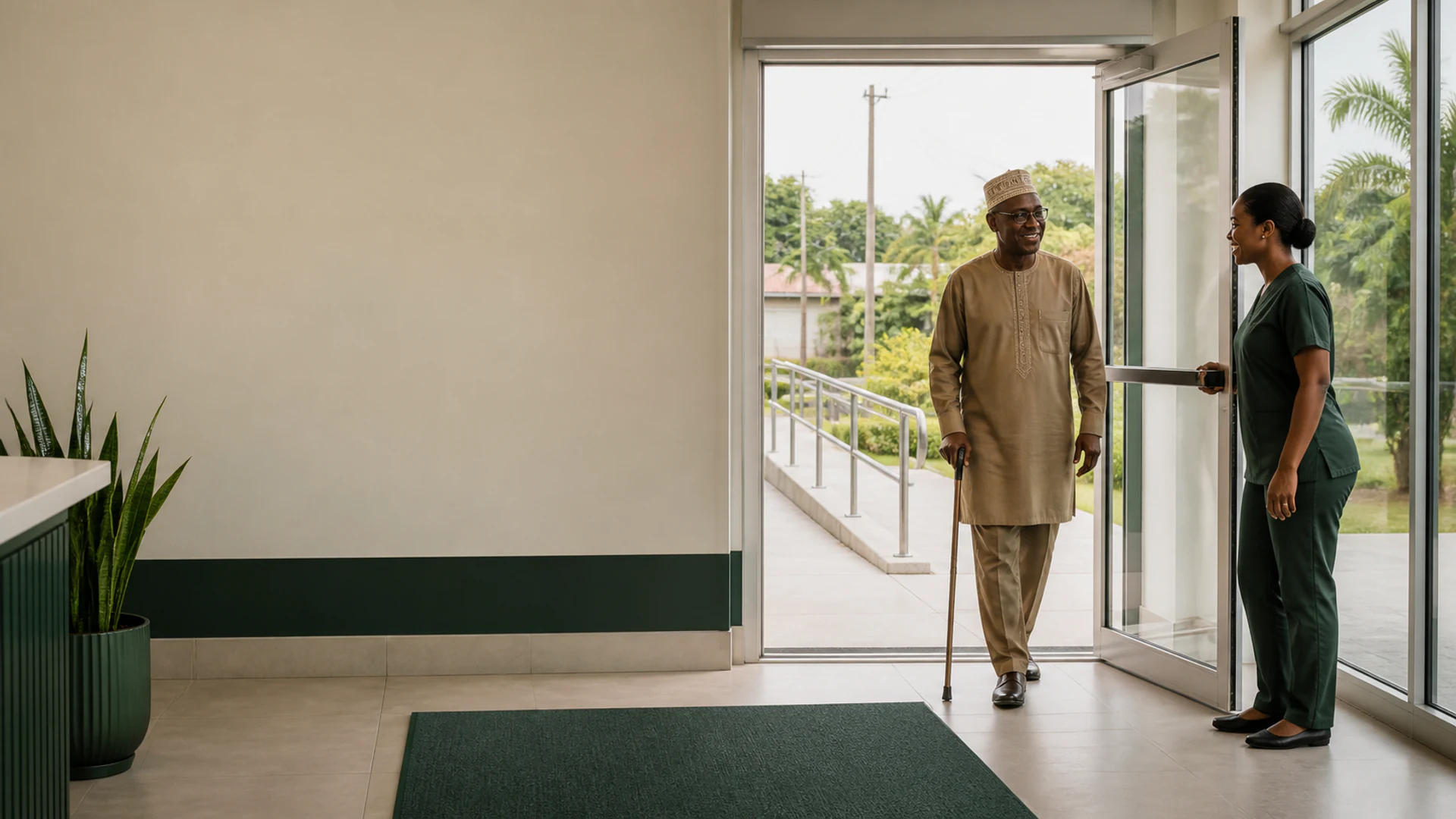 A staff member welcoming an older visitor through the accessible clinic entrance